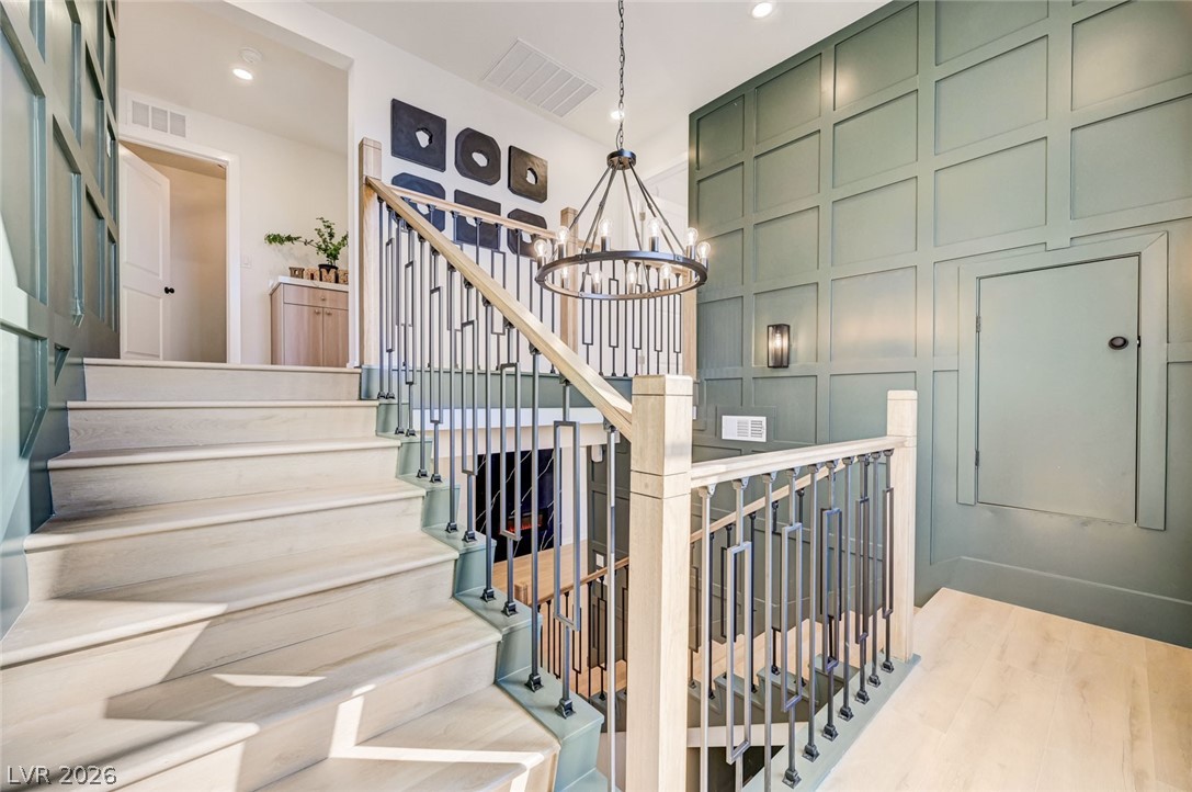 732 8th Street Boulder City, NV 89005 - Photo 8 of 15 Stairs with hanging lights, wood finished floors, and a decorative wall