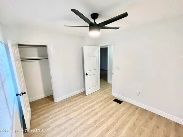 an empty room with wooden floor and a ceiling fan