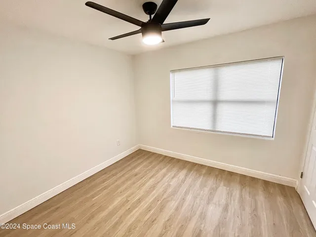 an empty room with a window and a ceiling fan