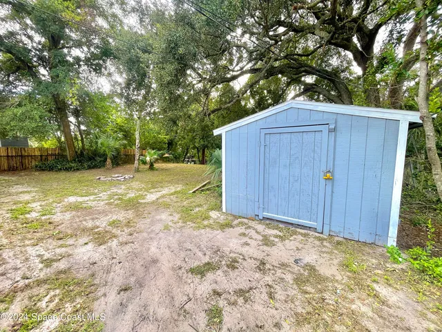 a view of backyard with wooden fence and large trees