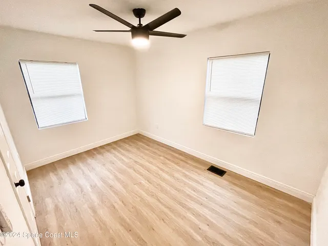 an empty room with a window and a ceiling fan