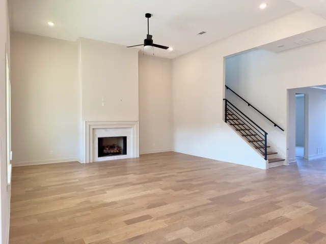 a view of an empty room with wooden floor fireplace and a window