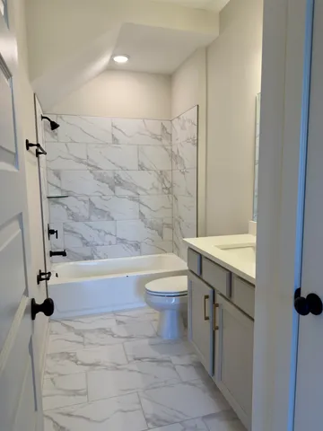 a bathroom with a granite countertop sink a toilet and bathtub