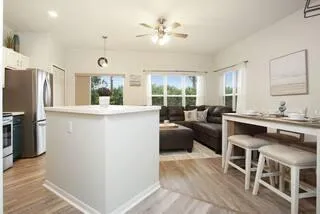 a kitchen with stainless steel appliances kitchen island granite countertop a refrigerator a oven a stove and a dining table with wooden floor