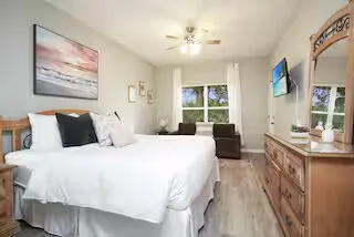 a spacious bedroom with a large bed a chandelier and a flat tv screen