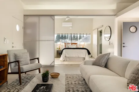 a living room with furniture and a large window with kitchen view