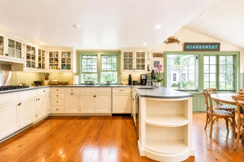 a large kitchen with granite countertop a stove and white cabinets next to a large window
