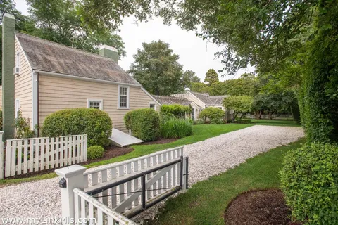 a view of a house with a small yard and a large tree