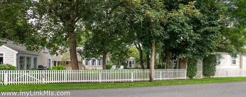 a view of a house with a small yard and large trees