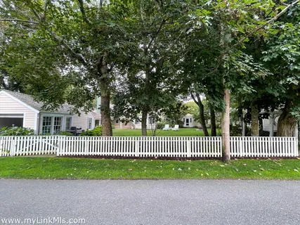 a view of a bench in front of a yard with wooden fence
