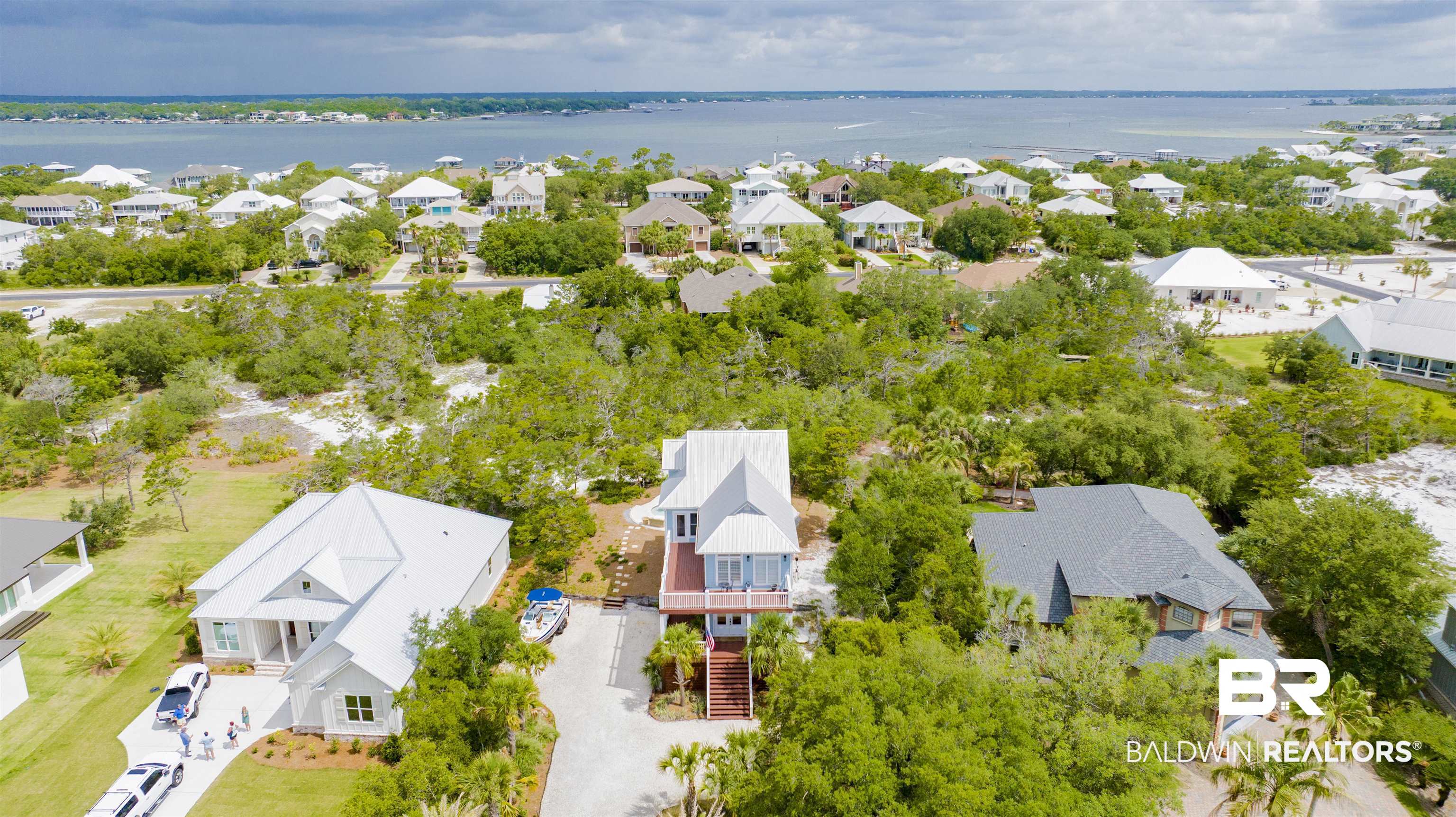 30351 River Road Orange Beach, AL 36561 - Photo 36 of 44 Coastal home featuring an elevated design, a prominent front deck, a white metal roof, and a gravel driveway