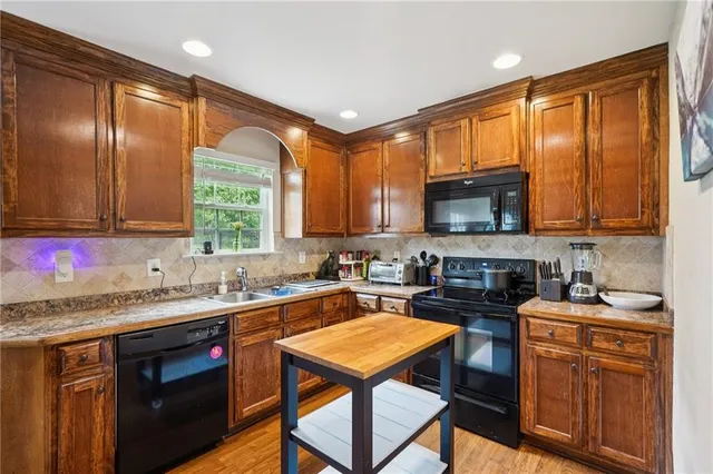 a kitchen with stainless steel appliances granite countertop a stove a sink a microwave and wooden cabinets