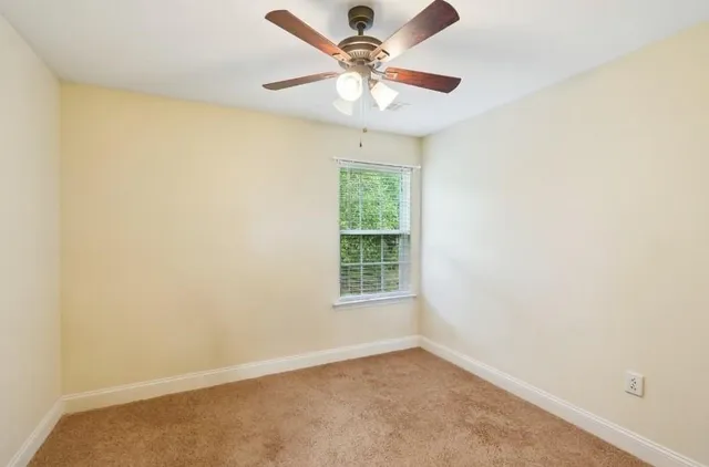 an empty room with a window and a fan