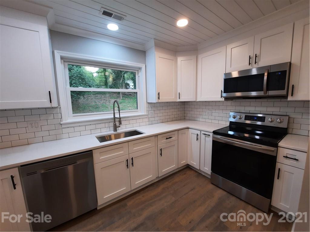 a kitchen with stainless steel appliances granite countertop a sink a stove a microwave a sink and cabinets