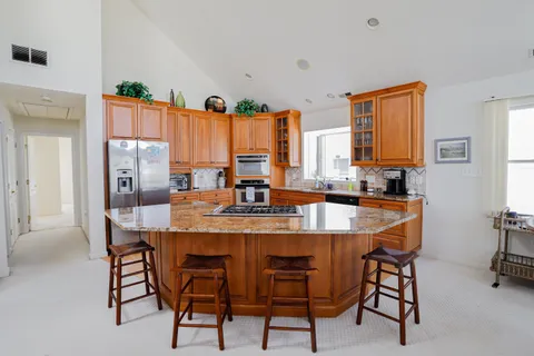 a dining hall with stainless steel appliances granite countertop a table and chairs
