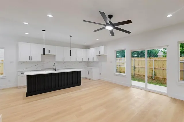 a large kitchen with stainless steel appliances a large counter top a stove and a refrigerator