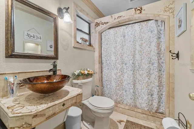 a bathroom with a granite countertop toilet and a sink