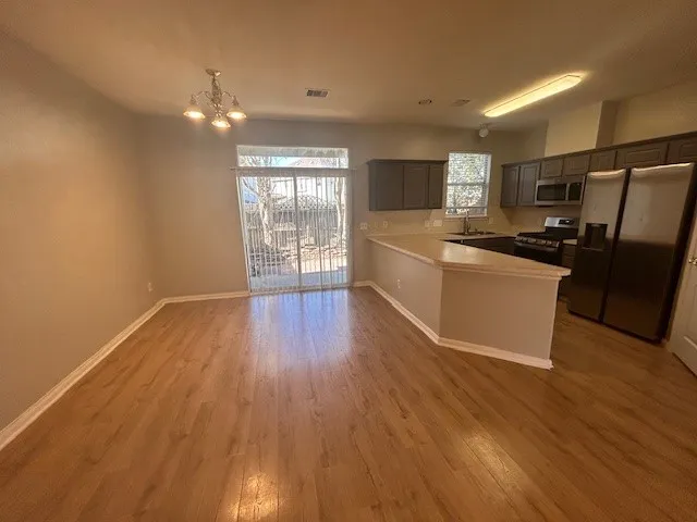 a kitchen with stainless steel appliances a refrigerator a sink dishwasher and a stove with wooden floor