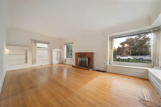 a view of an empty room with a window and fire place
