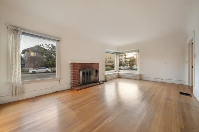 an empty room with wooden floor and fireplace