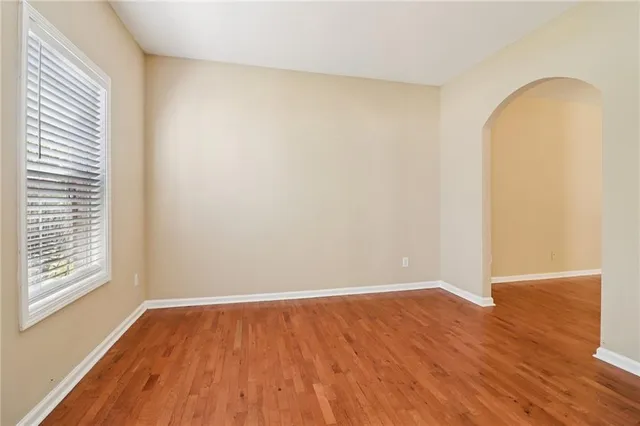 a view of an empty room with wooden floor and a fireplace