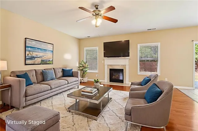 a view of an empty room with wooden floor and a ceiling fan