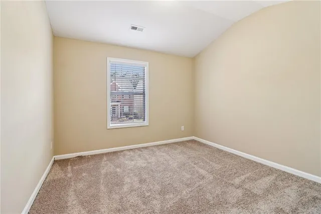 a view of an empty room with closet and a window