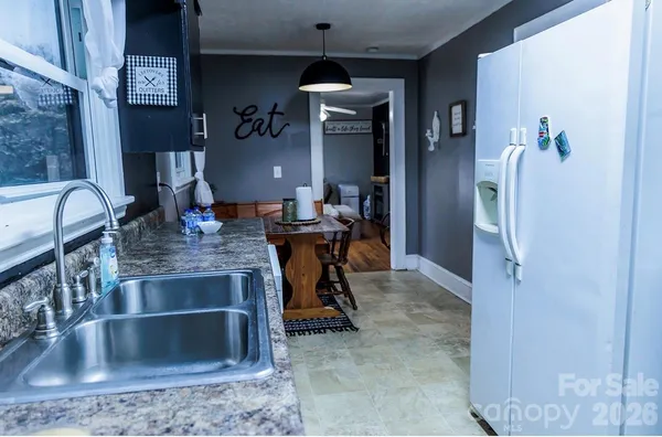 a kitchen counter top space with granite countertop a sink and a refrigerator