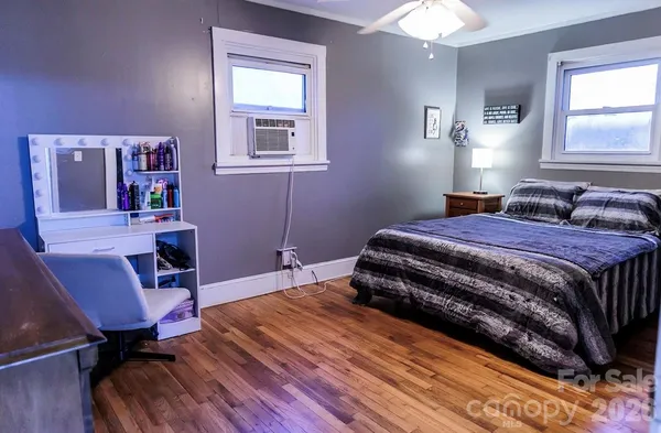 a bedroom with a bed a desk and chair with wooden floor