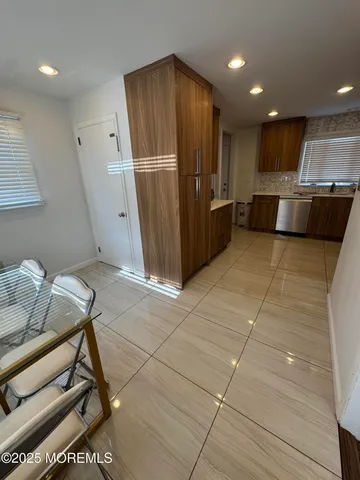 a view of kitchen with stainless steel appliances wooden floor and living room view