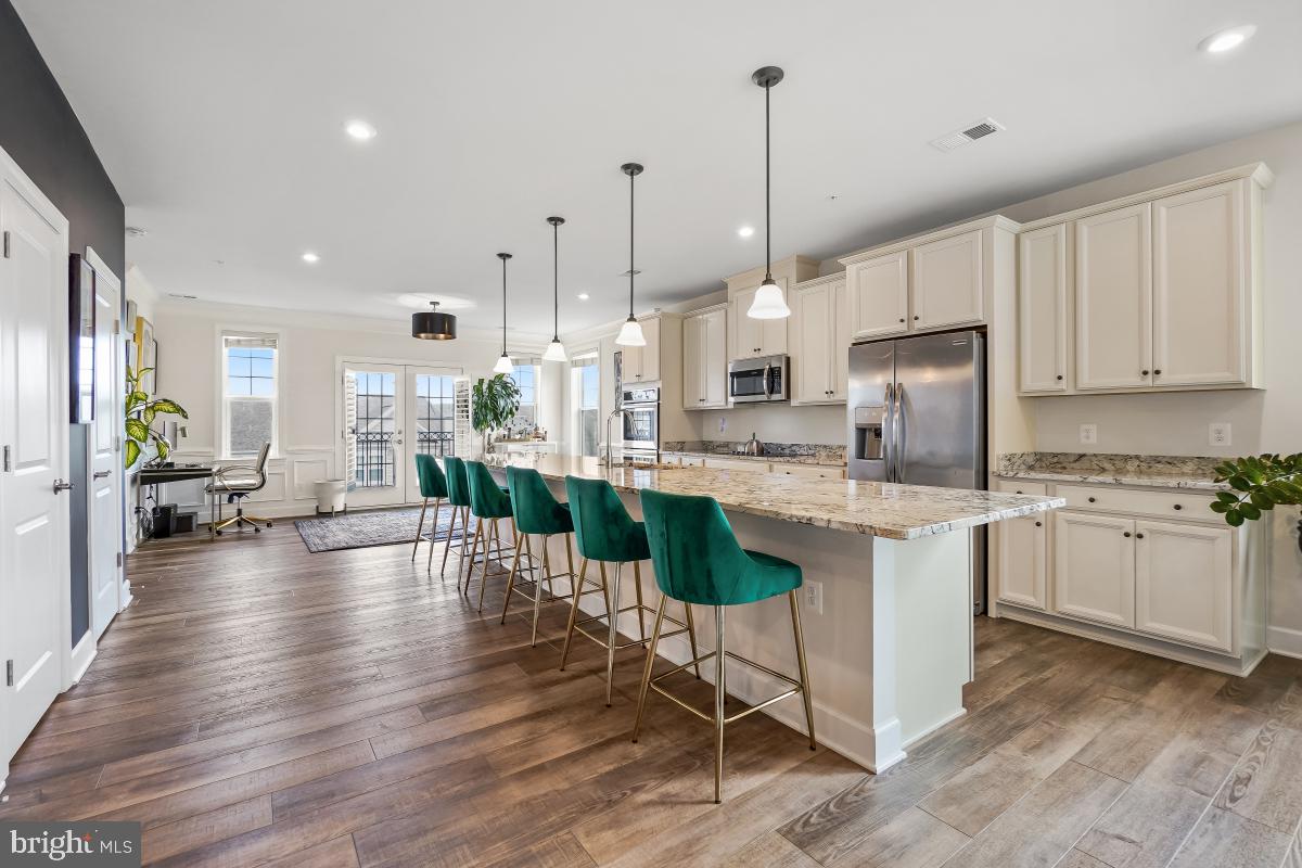 2945 Duvall Ridge Road, Unit 573 Hyattsville, MD 20785 - Photo 2 of 23 a open kitchen with granite countertop a stove a sink a dining table and chairs with wooden floor