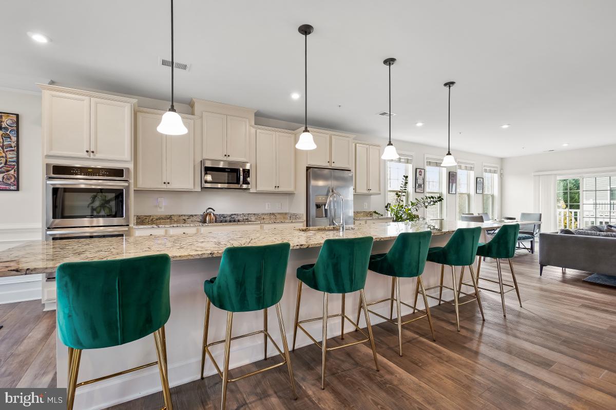 2945 Duvall Ridge Road, Unit 573 Hyattsville, MD 20785 - Photo 5 of 23 a kitchen with stainless steel appliances kitchen island granite countertop a dining table chairs and white cabinets