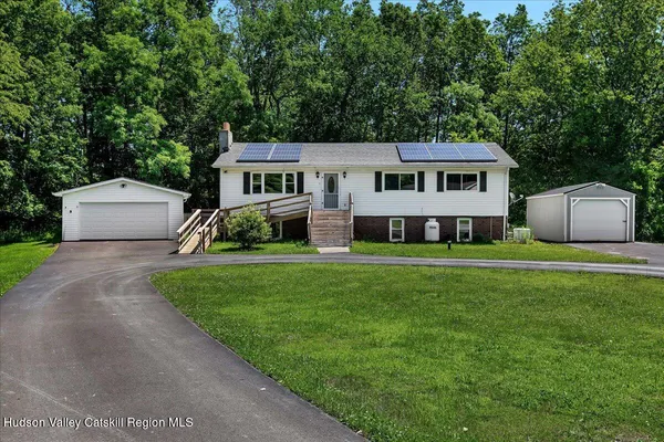 a front view of a house with a garden and trees