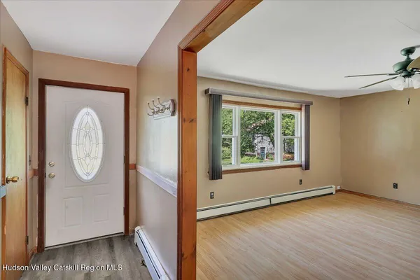 an empty room with wooden floor mirror and windows