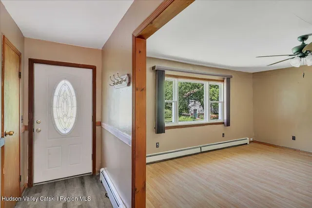 an empty room with wooden floor mirror and windows