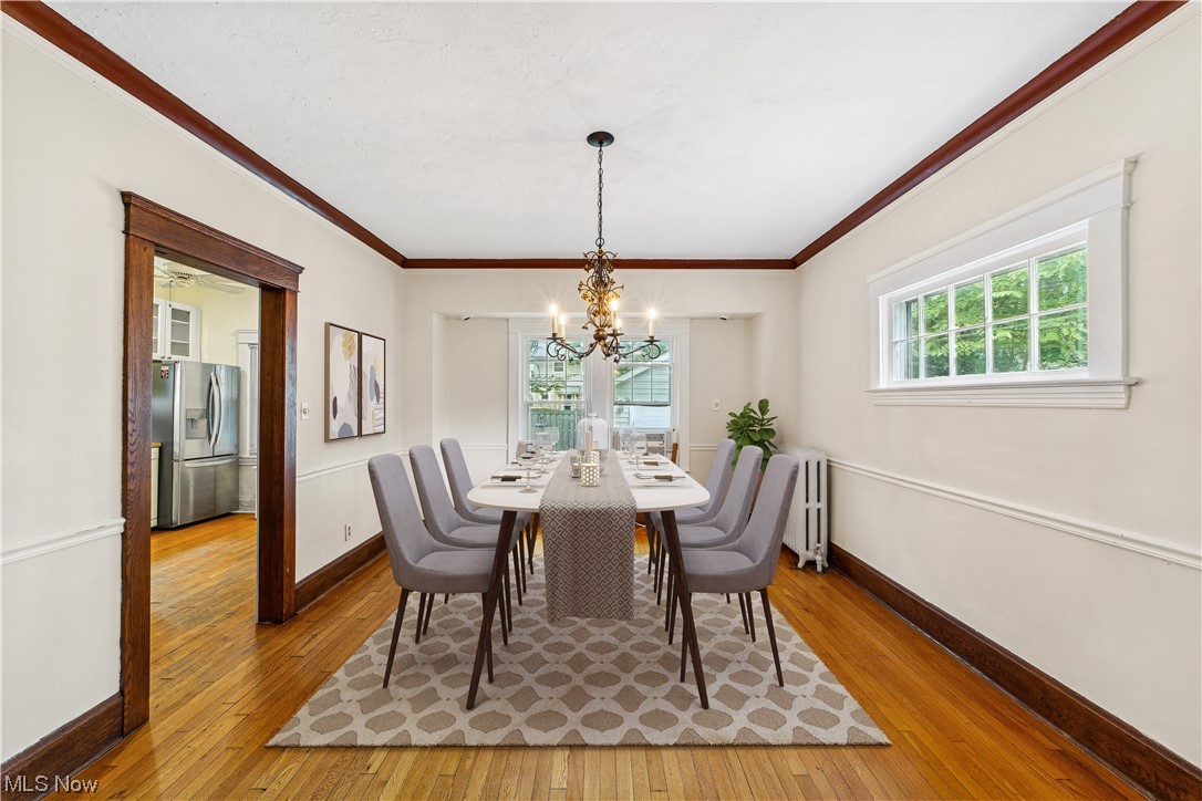 3045 East Overlook Road Cleveland, OH 44118 - Photo 7 of 29 Virtually staged dining space with radiator, light hardwood / wood-style floors, crown molding, and a notable chandelier