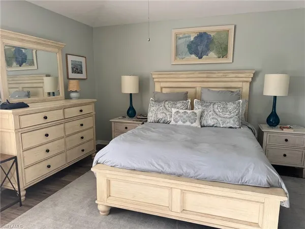 a bedroom with a bed and a lamp on dresser
