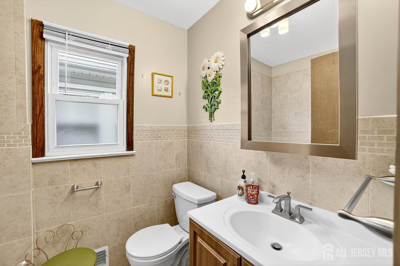 307 Sutton Street Perth Amboy, NJ 08861 - Photo 12 of 27 a bathroom with a sink mirror and toilet