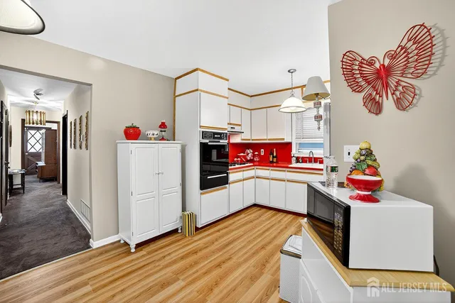 a kitchen with stainless steel appliances a white cabinets and wooden floor