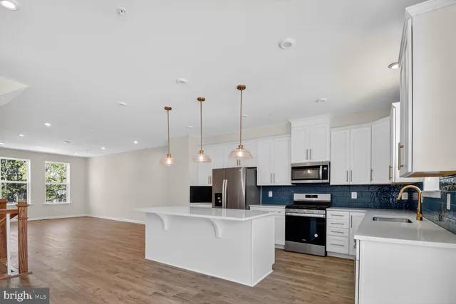 a open kitchen with stainless steel appliances kitchen island granite countertop a stove top oven a sink a counter top space and cabinets