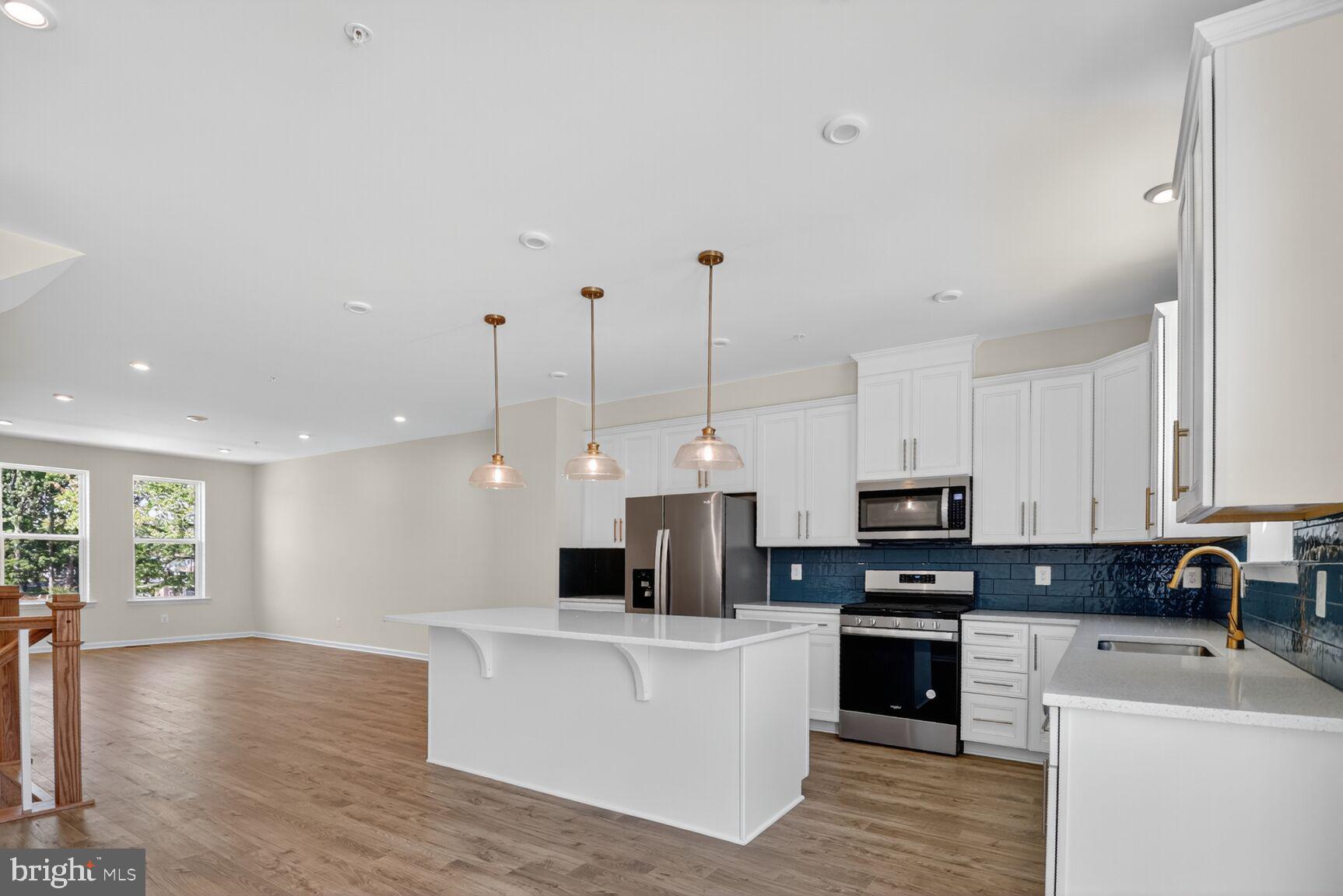 a open kitchen with stainless steel appliances kitchen island granite countertop a stove top oven a sink a counter top space and cabinets