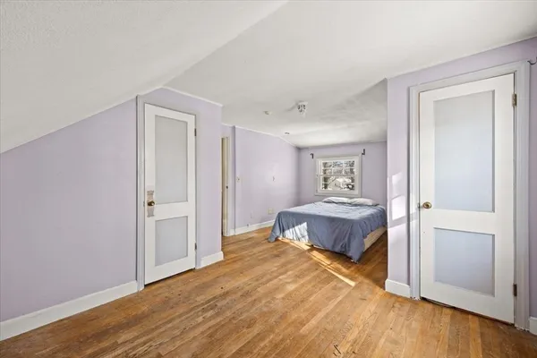 a spacious bedroom with a bed and wooden floor