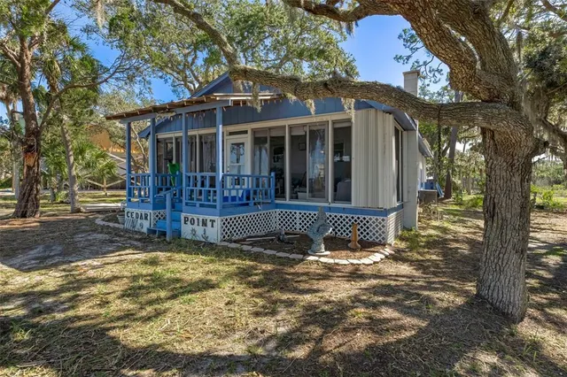 a view of a house with a small yard and large tree