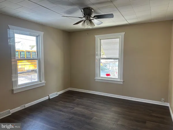 a view of an empty room with window and wooden floor