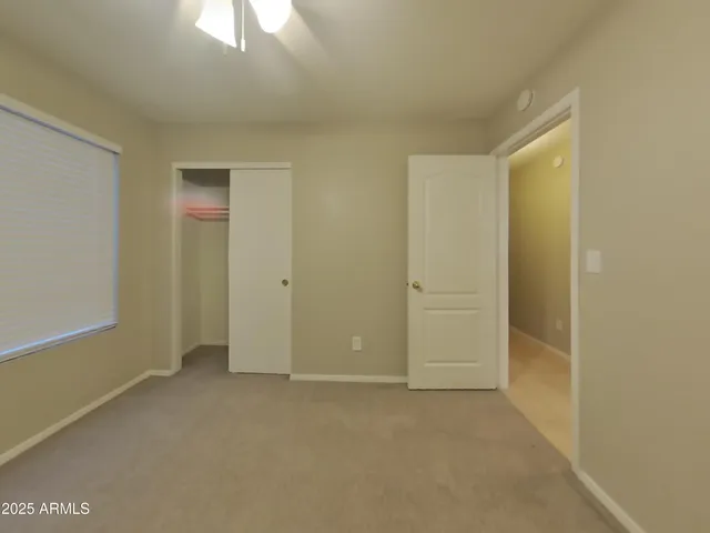 an empty room with a fan & a window