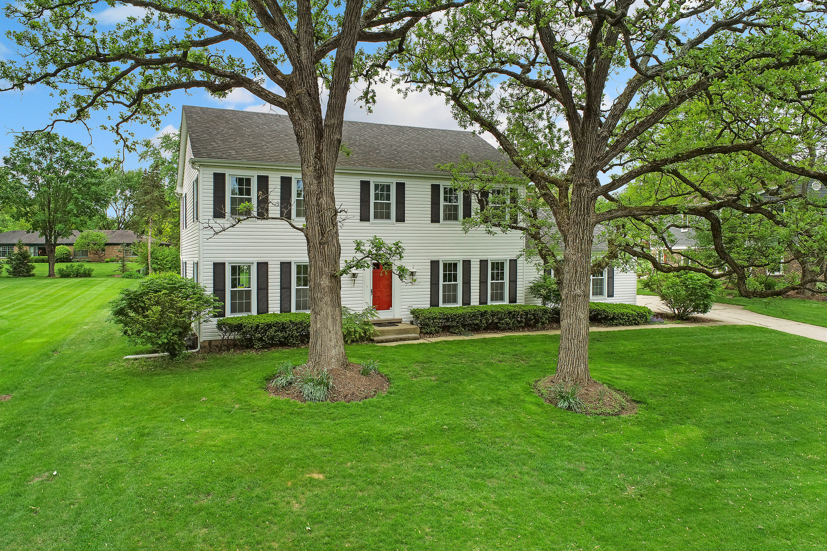 a front view of a house with garden and trees