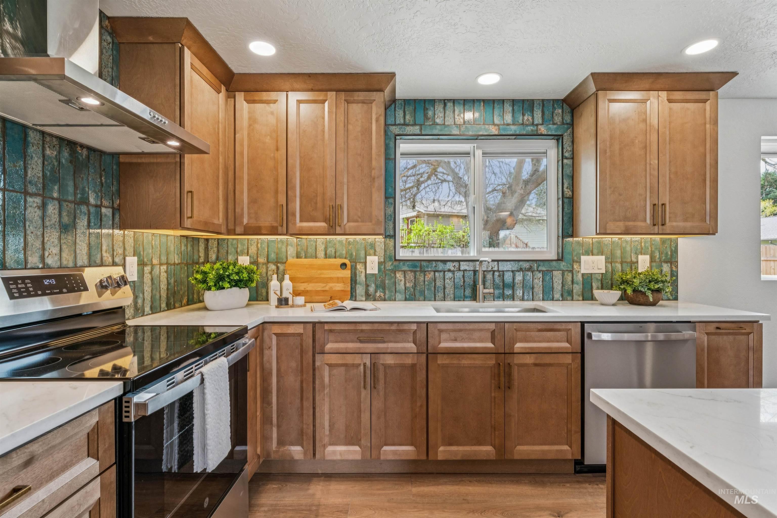 9709 West McMillan Road Boise, ID 83704 - Photo 14 of 50 Kitchen featuring stainless steel appliances, wood finish cabinets, backsplash, light stone countertops, and a textured ceiling