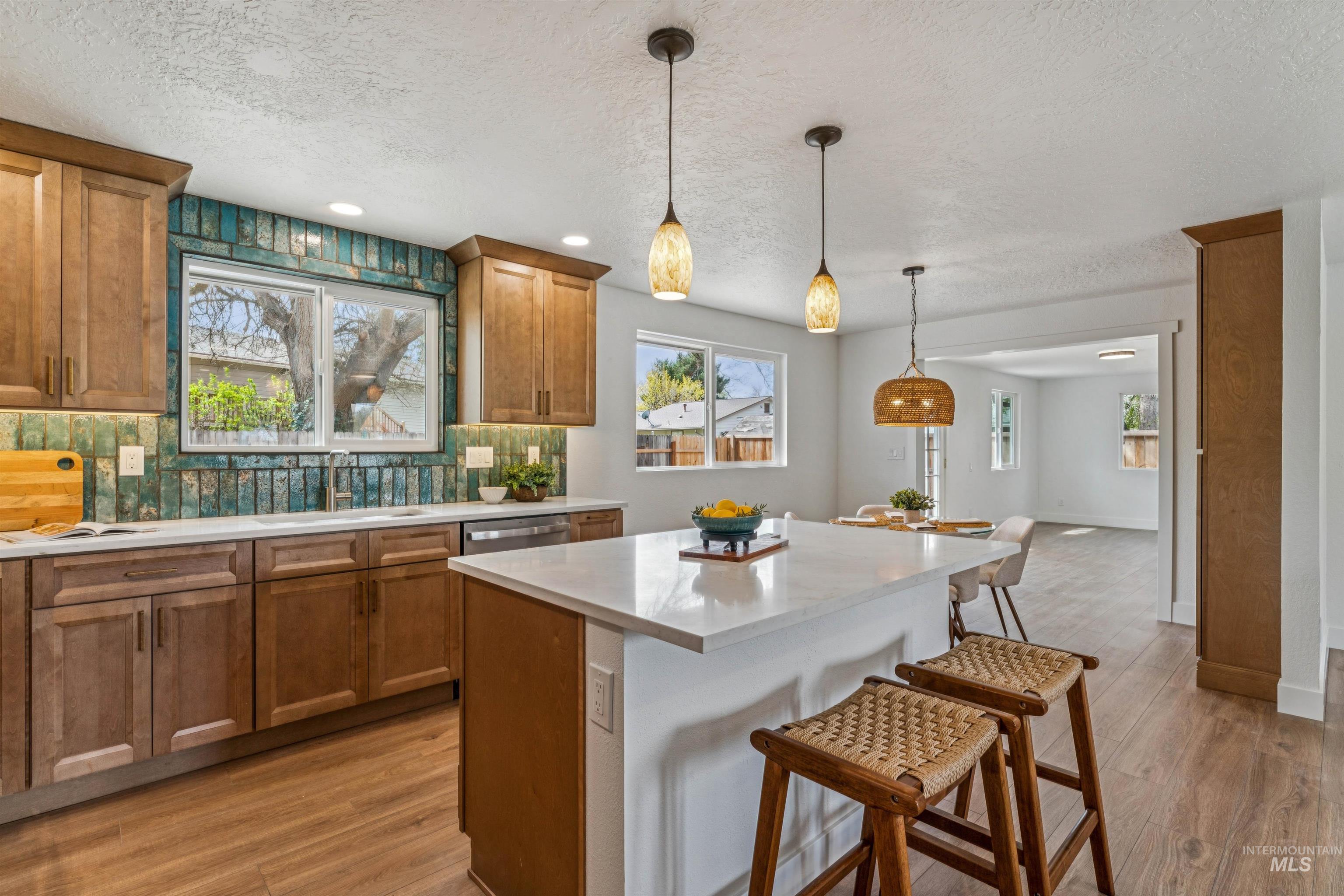 9709 West McMillan Road Boise, ID 83704 - Photo 15 of 50 Kitchen with tasteful backsplash, wood finish cabinets, a kitchen bar, hanging light fixtures, and light wood-style flooring