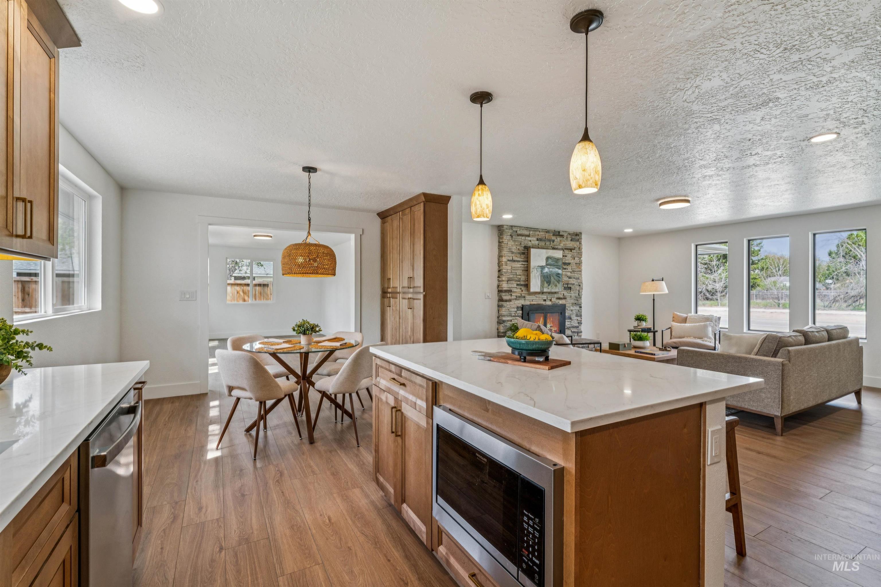 9709 West McMillan Road Boise, ID 83704 - Photo 50 of 50 Kitchen with stainless steel appliances, wood finish cabinets, open floor plan, light stone counters, and a fireplace