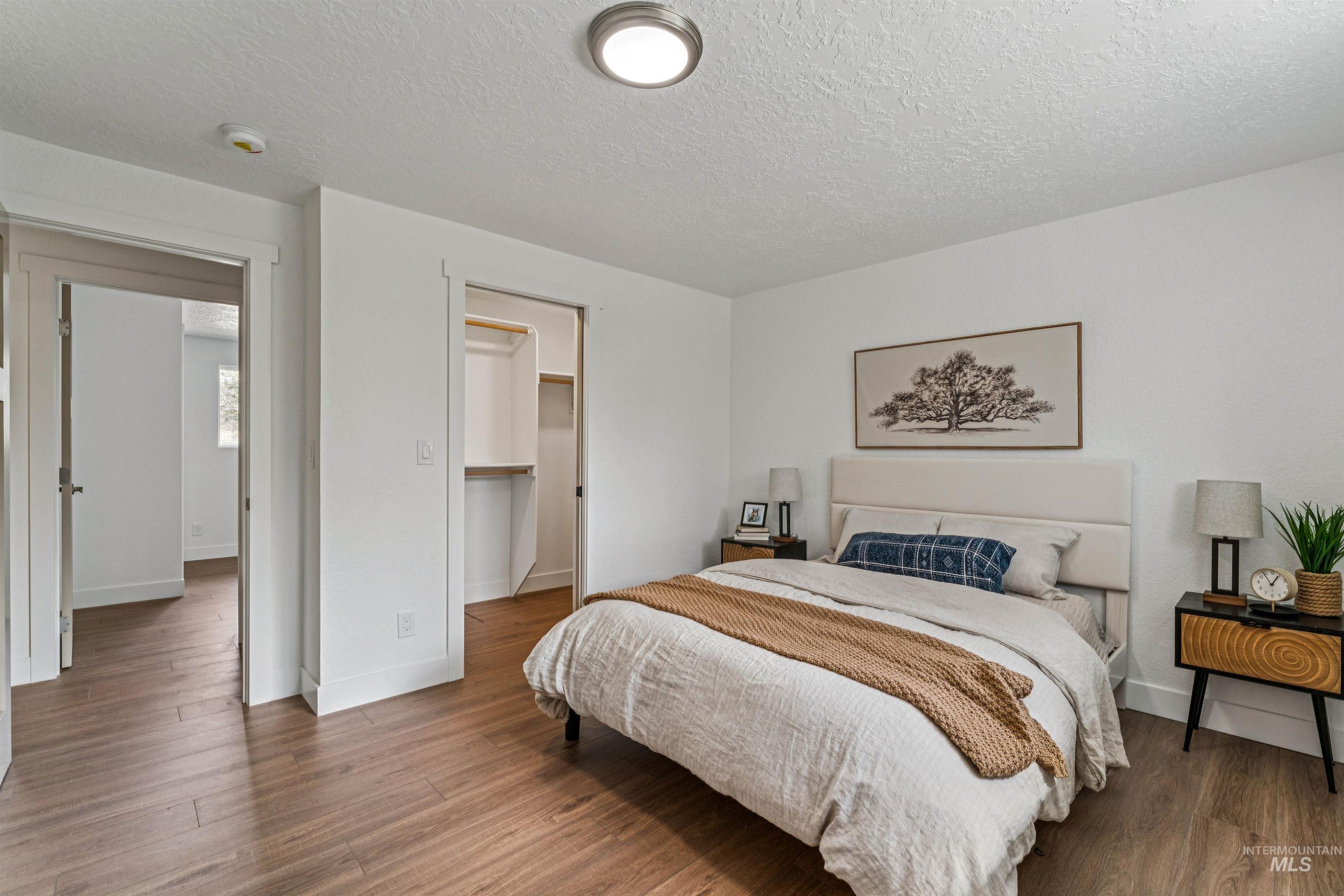 9709 West McMillan Road Boise, ID 83704 - Photo 23 of 50 Bedroom with a walk in closet, wood finished floors, and a textured ceiling